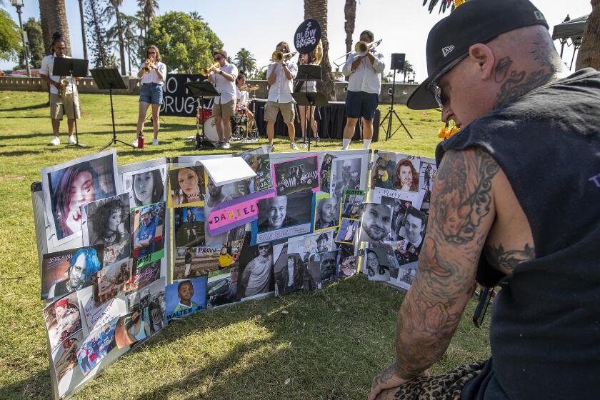 LOS ANGELES, CA-AUGUST 31, 2023:Kent Avery of Los Angeles looks at photographs of people who all died from drug overdoses, during an event at MacArthur Park on International Overdose Awareness Day. Avery said that 3 of his friends who died from drug overdoses were pictured in the display. (Mel Melcon / Los Angeles Times)