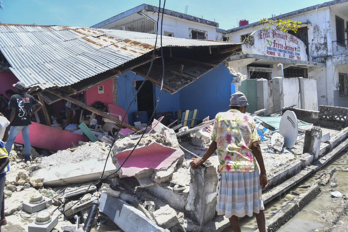 A woman stands in front of a destroyed home in the aftermath of an earthquake in Les Cayes, Haiti, Saturday, Aug. 14, 2021. A 7.2 magnitude earthquake struck Haiti on Saturday, with the epicenter about 125 kilometers ( 78 miles) west of the capital of Port-au-Prince, the US Geological Survey said. (AP Photo/Duples Plymouth)