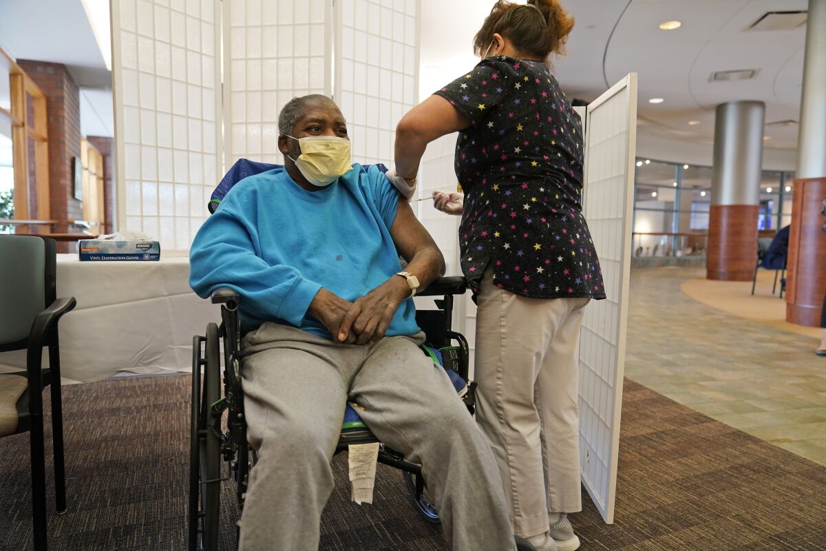 FILE - Edward Williams, 62, a resident at the Hebrew Home at Riverdale, receives a COVID-19 booster shot in New York, Sept. 27, 2021. COVID-19 infections are soaring again at U.S. nursing homes because of the omicron wave, and deaths are climbing too. That's leading to new restrictions on family visits and a renewed push to get more residents and staff members vaccinated and boosted. (AP Photo/Seth Wenig, File)