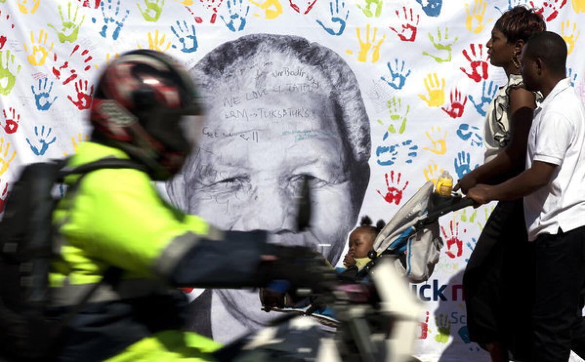 A couple walks past a banner depicting former South African President Nelson Mandela last week outside the Pretoria hospital where he is being treated.