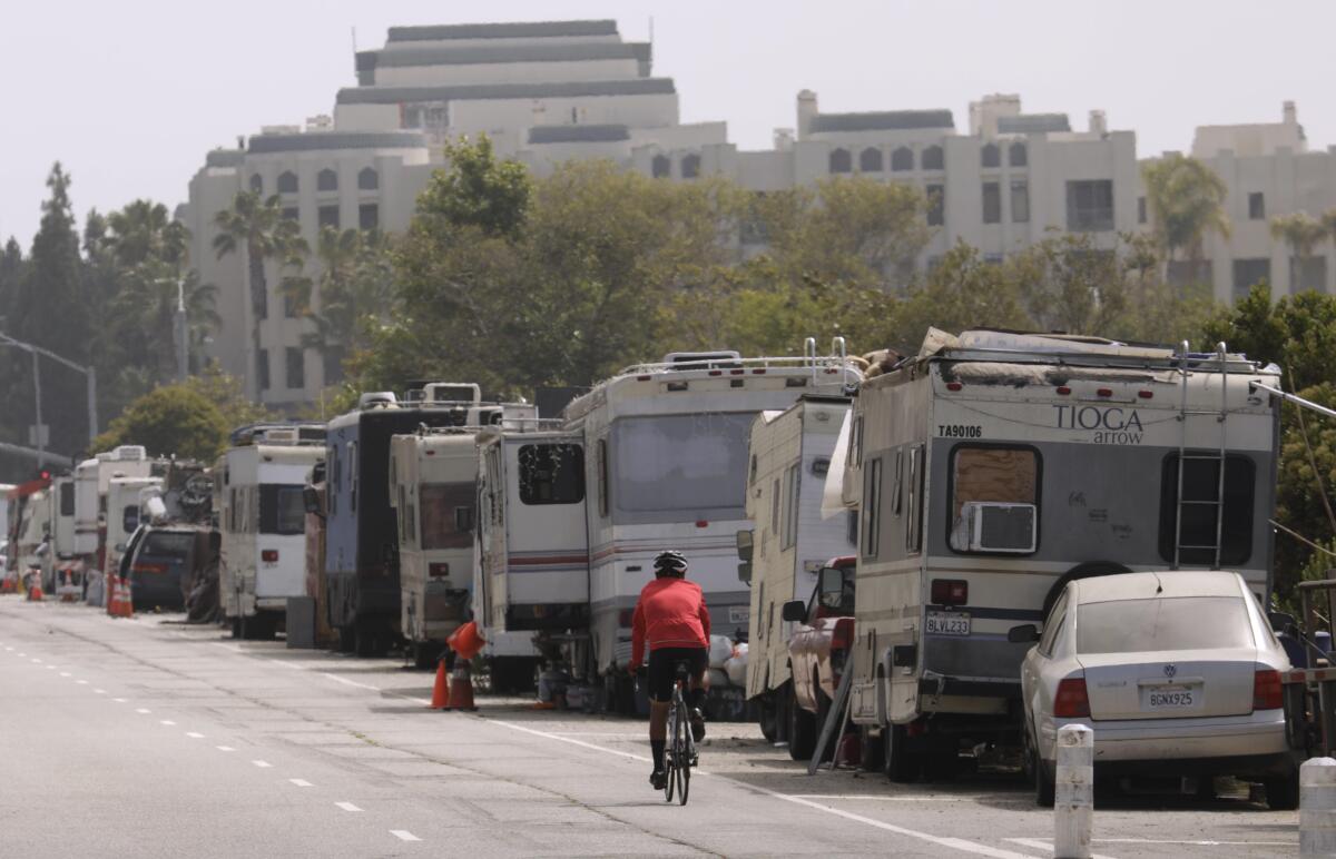 A cyclist rides past RVs that make up a homeless encampment in Marina del Rey. 