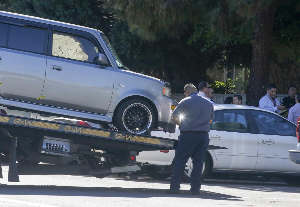 A tow truck operator removes a vehicle, with a blood-stained window, after an occupant of the vehicle was found dead in the 2300 block of Vanguard Way in Costa Mesa Wednesday morning.