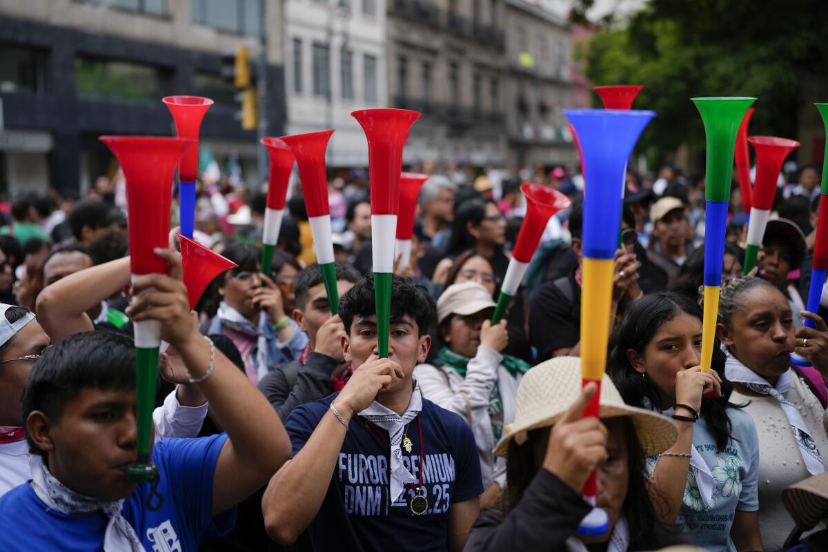 Varias personas tocan cornetas en una marcha a favor de la reforma judicial 