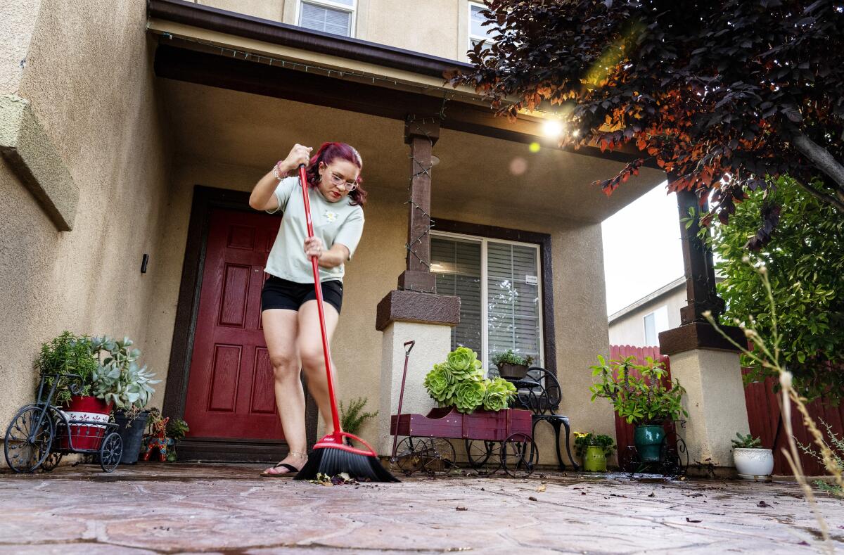 A woman sweeps porch of home.