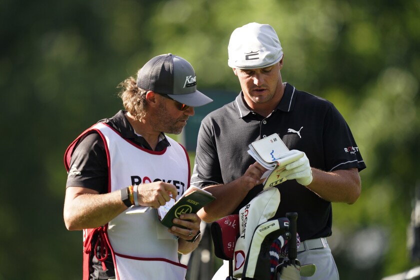 Caddie Ben Schomin, left, and Bryson DeChambeau look over notes on the ninth hole during the first round of the Rocket Mortgage Classic golf tournament, Thursday, July 1, 2021, at the Detroit Golf Club in Detroit. DeChambeau, is defending his Rocket Mortgage Classic title with a new caddie. The 2020 U.S. Open champion and Tim Tucker mutually agreed to part ways, according to Brett Falkoff of GSE Worldwide, who manages DeChambeau. Falkoff said Cobra-Puma Golf tour operations manager Schomin will be DeChambeau's caddie this week. (AP Photo/Carlos Osorio)