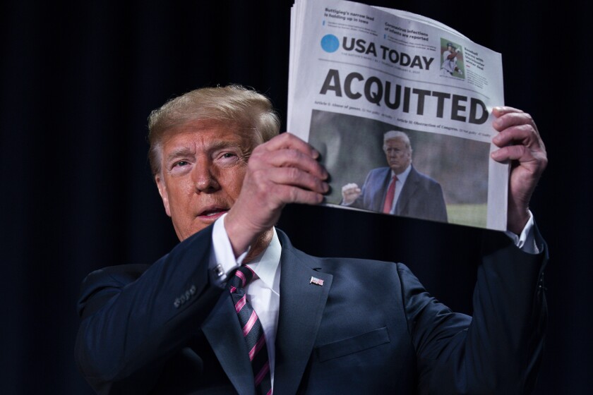 FILE - In this Feb. 6, 2020, file photo, President Donald Trump holds up a newspaper with the headline that reads "ACQUITTED" at the 68th annual National Prayer Breakfast, at the Washington Hilton in Washington. (AP Photo/ Evan Vucci, File)