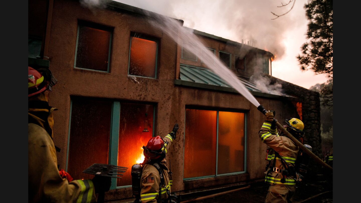Atascadero Firefighters try to control flames burning inside a home along Highway 29 in Calistoga on Oct. 12.