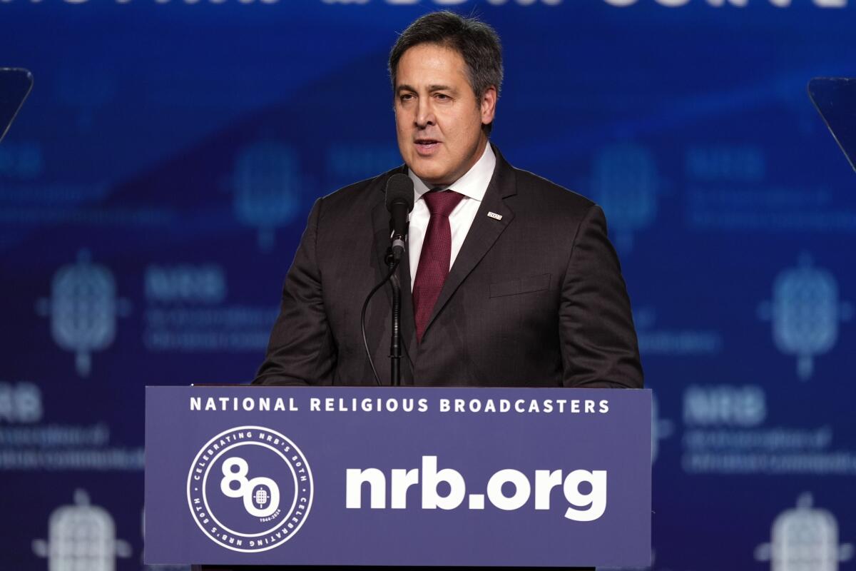 A man speaks at a lectern with a sign that says, "National Religious Broadcasters, nrb.org"