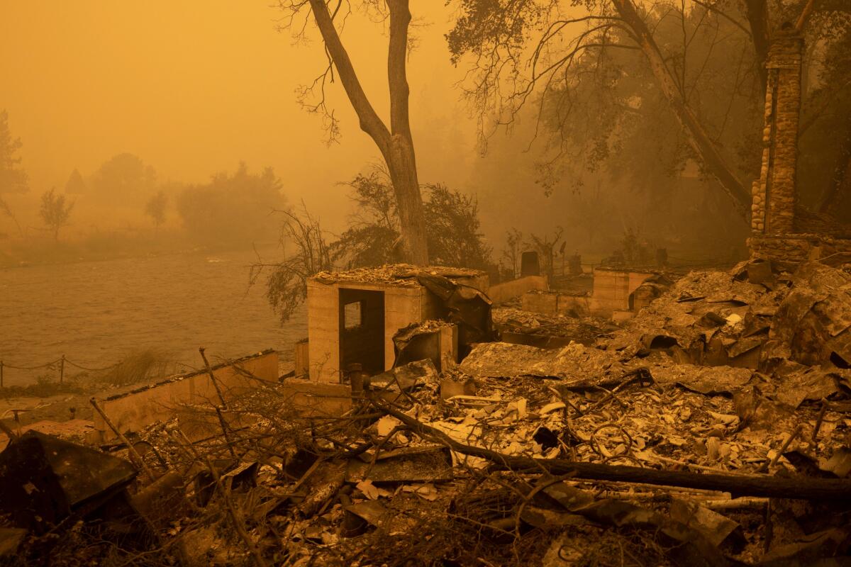A destroyed building is surrounded by a haze of wildfire smoke.