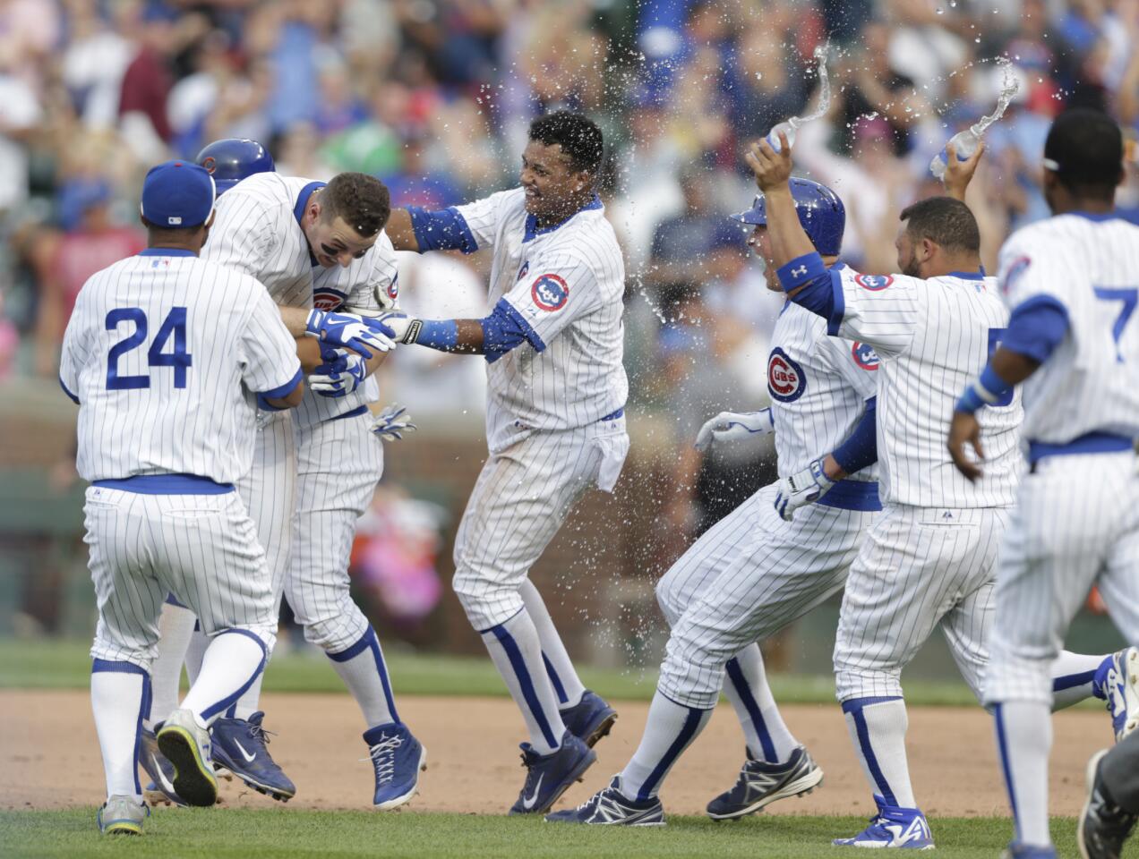 Anthony Rizzo is swarmed by his teammates after hitting the game-winning hit in the 12th inning.