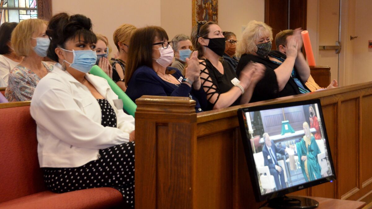 Irene Vecchione in white jacket, sits among the congregation at St. James Episcopal Church in Newport Beach.