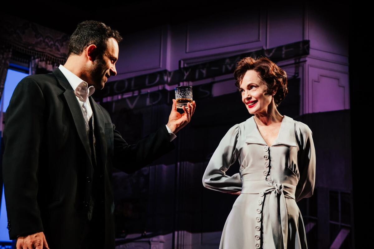 Aaron Costa Ganis holds up A drink as he stands beside Elizabeth McGovern in "Ava: The Secret Conversations."