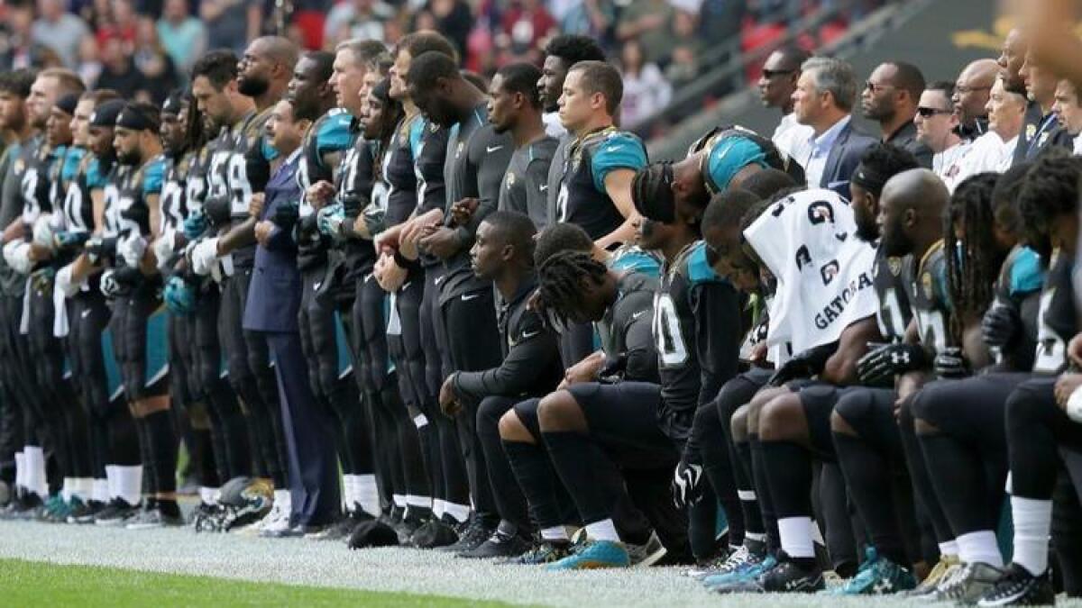 Members of the Jacksonville Jaguars lock arms with owner Shad Khan while some kneel before the start of a Sept. 24 game in London against the Baltimore Ravens.