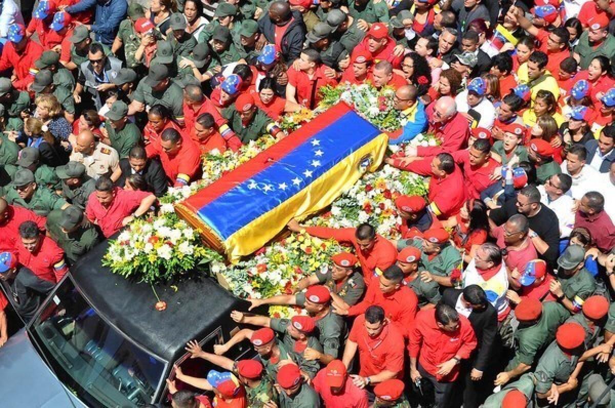 President Hugo Chavez's coffin is thronged as it is carried through Caracas to the Venezuelan Military Academy, where his body will lie in state until a funeral Friday.