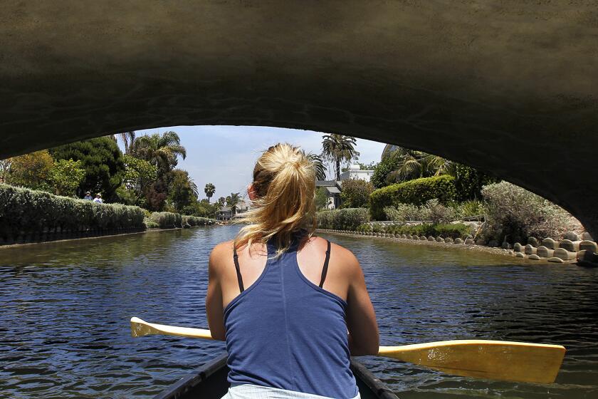 Brigette Edler rows a boat under a bridge at the Venice Canals.