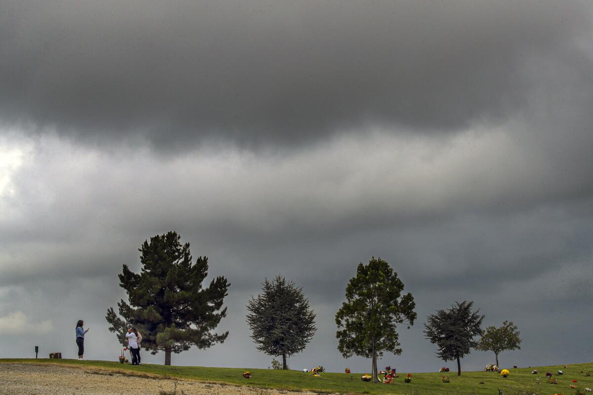 A family visits a loved one at Forest Lawn Cemetery on a cloudy Saturday morning in Covina.