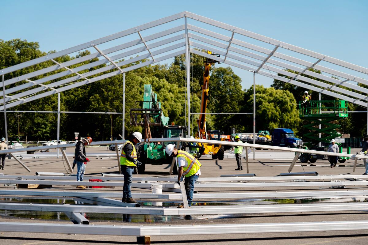 Workers erect the frame of an airplane hangar-sized tent