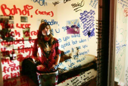 Danielle Sherzer, a cousin of one of the shooting victims, is reflected amid messages from family and friends that cover the mirrored closet doors in Bodhisattva "Bodhi" Sherzer-Potter's bedroom.