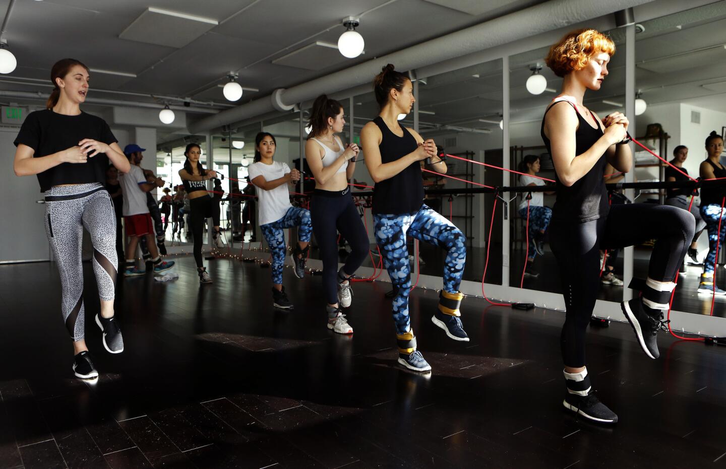 Trainer Keely Ahrold, left, instructs participants in a ModelFIT sculpt class as they use bands to create resistance.