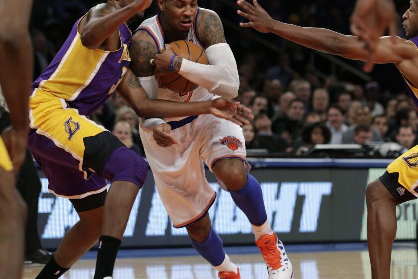 Carmelo Anthony protects the ball as he drives past Los Angeles Lakers forward Devin Ebanks.