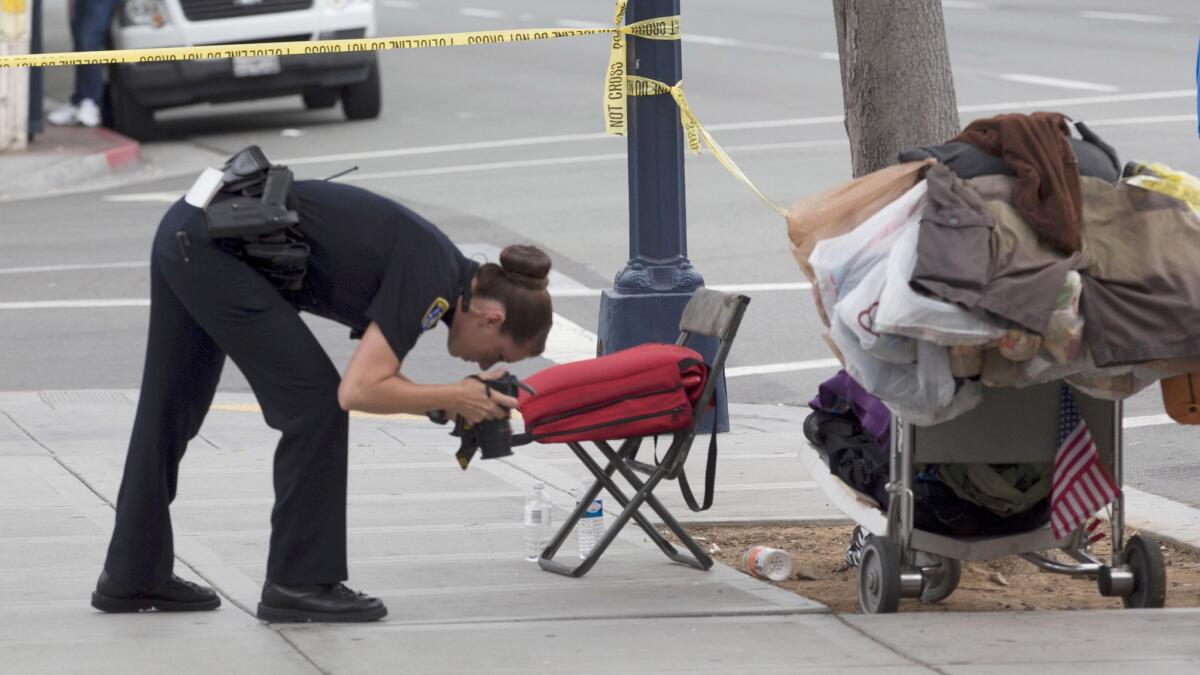 A San Diego police officer takes photos at the scene where a homeless man was attacked by a man with a hammer Wednesday morning.