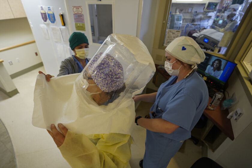 Staff member gets help putting on safety gear before entering a negative pressure room at Sharp Memorial Chula Vista Intensive Care Unit on June 24th, 2020 in Chula Vista. Speaking to doctors, nurses and healthcare staff helping patients with Covid-19 at three South Bay hospitals.