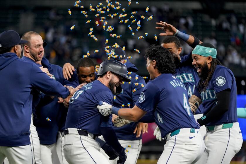 Mitch Haniger, centro, de los Marineros de Seattle, es rociado con chicles por parte de sus compañeros después de impulsar la carrera de la victoria contra los Medias Blancas de Chicago durante la décima entrada el miércoles 12 de junio de 2024, en Seattle. (AP Foto/Lindsey Wasson)