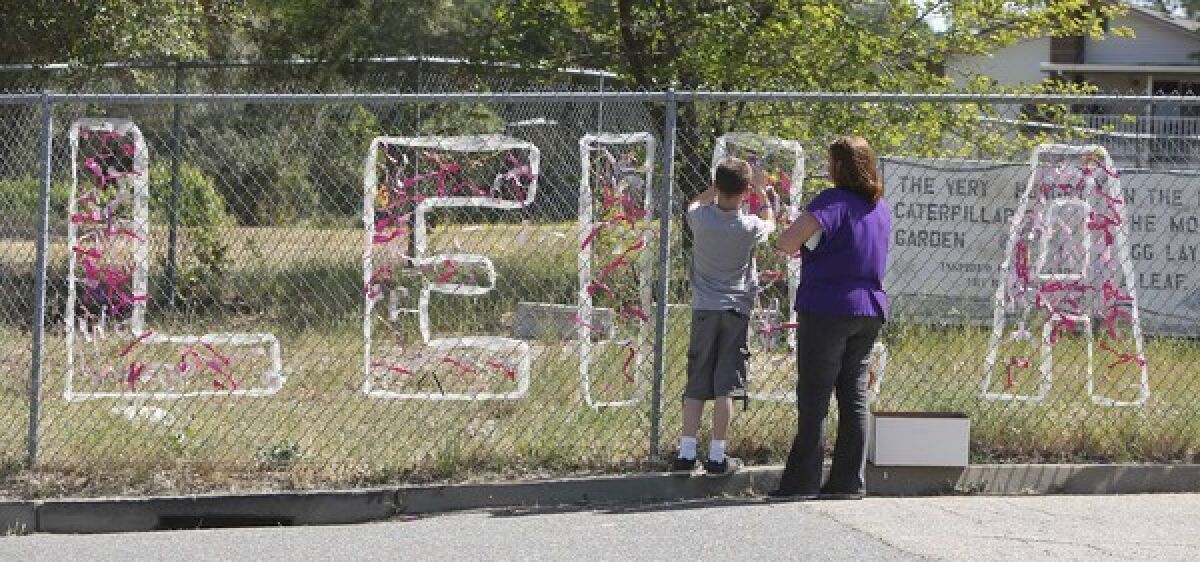 Teacher Cecilia Richardson helps a student tie a ribbon honoring murder victim, A student ties a ribbon to a fence honoring Leila Fowler at Jenny Lind Elementary School in Valley Springs, Calif., after the third-grader was stabbed to death at her home.
