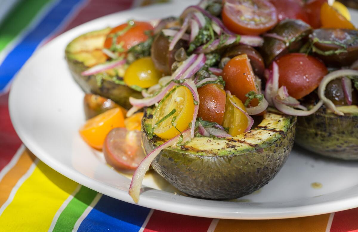 A salad with halved avocados and sliced grape tomatoes.