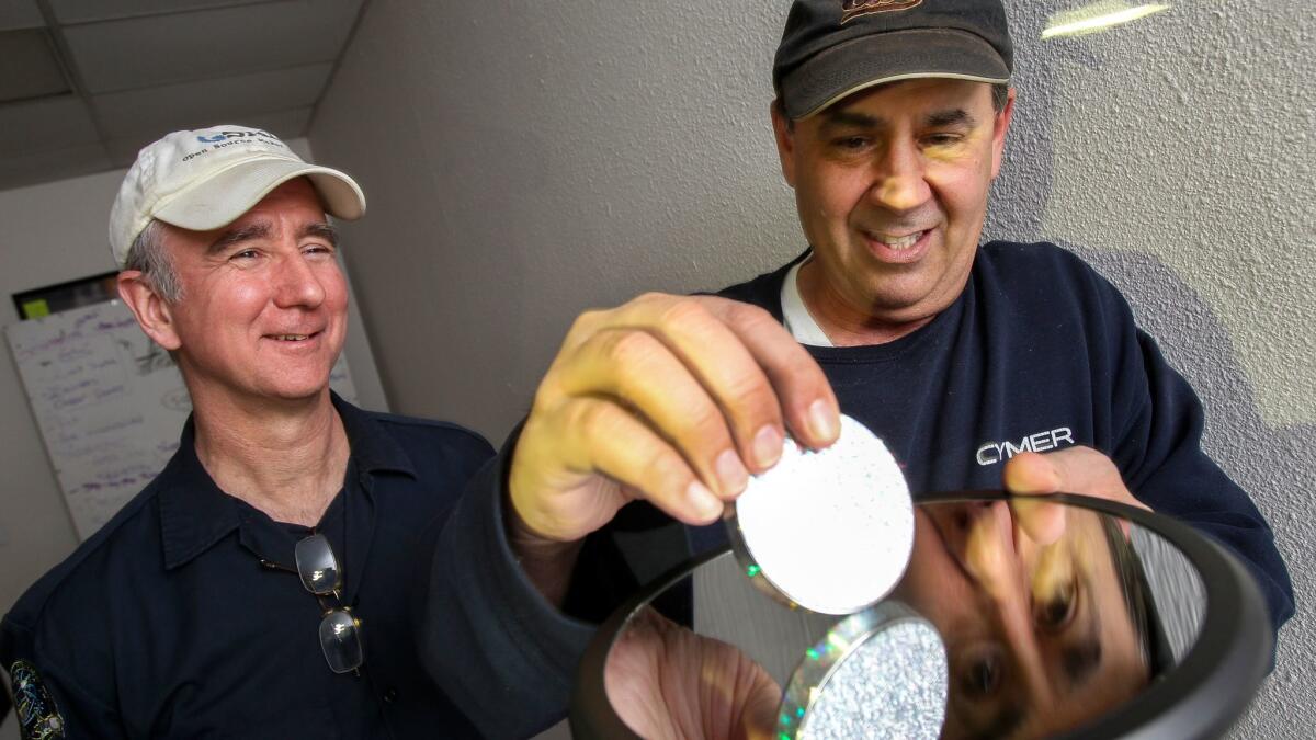 Joe Bendik, right, demonstrates his Euler's Disk science toy for Dan Hendricks, cofounder of the Open Source Maker Labs, at the Vista labs on March 14.