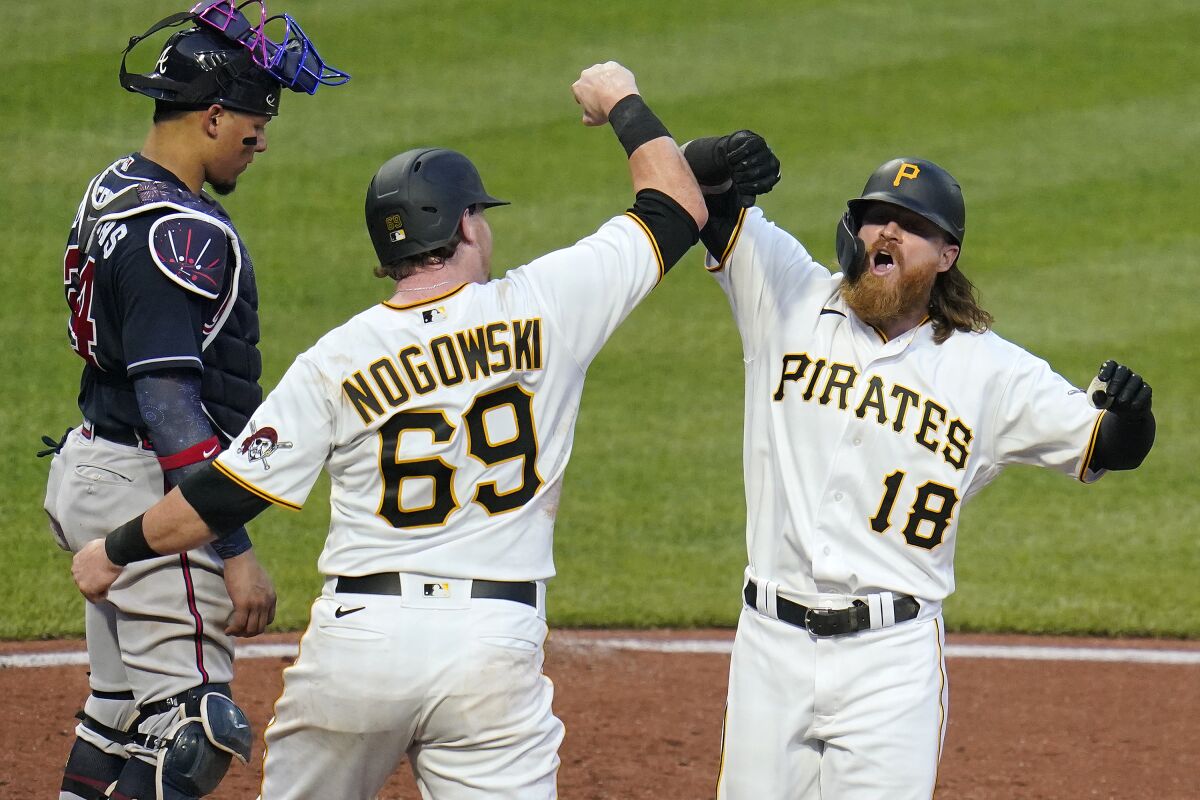 Pittsburgh Pirates' Ben Gamel (18) celebrates with teammate John Nogowski (69) as he crosses home plate in front of Atlanta Braves catcher William Contreras after hitting a two-run home run off starting pitcher Max Fried during the fourth inning of a baseball game in Pittsburgh, Monday, July 5, 2021. (AP Photo/Gene J. Puskar)