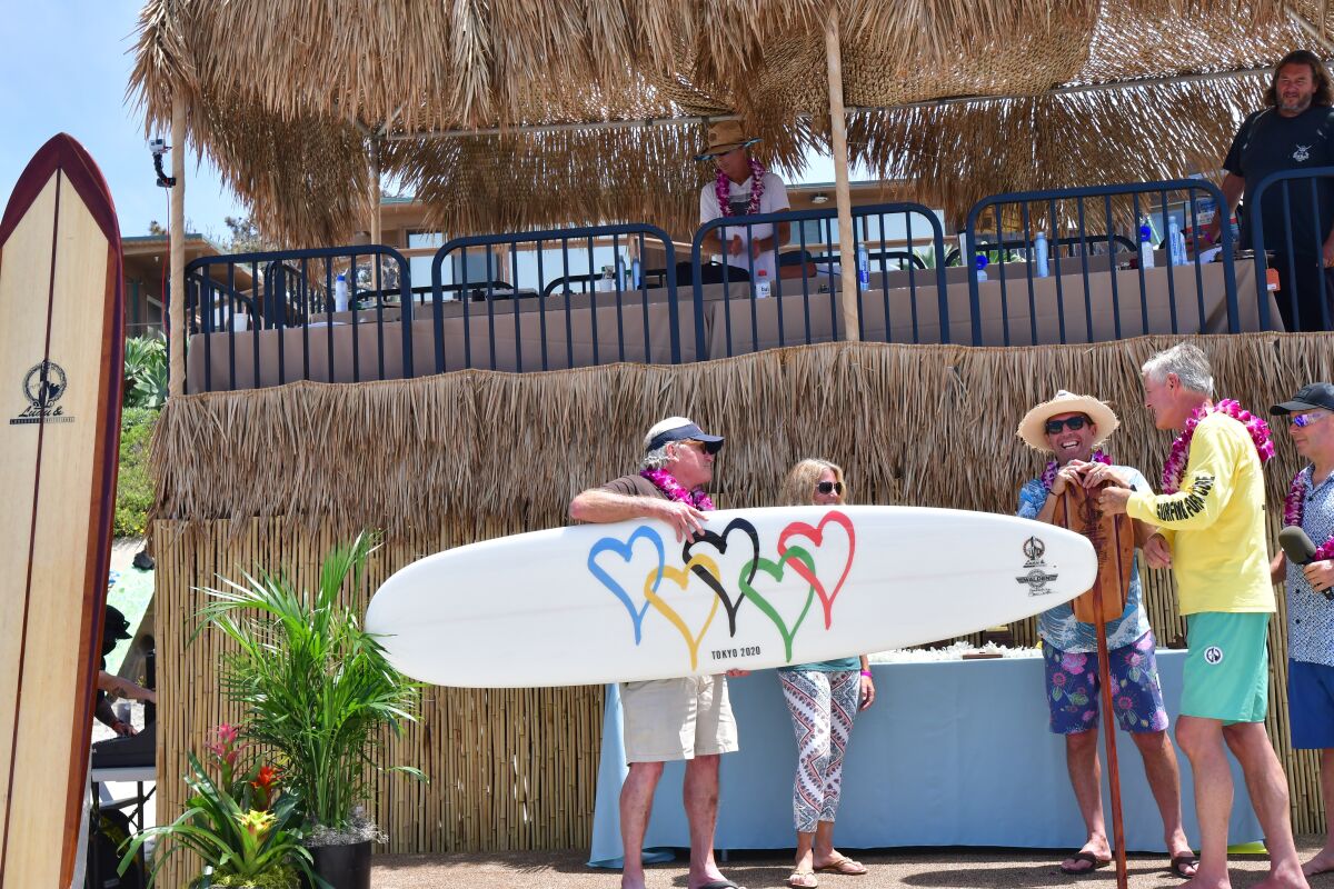 Surfboard maker Steve Walden presents a custom surfboard to be auctioned off