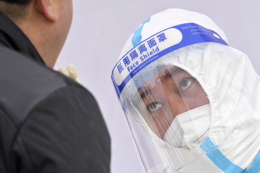 A medical worker's face shield fogs up as he takes sample from a resident during a second round of COVID-19 testing in northern China's Tianjin Municipality on Wednesday, Jan. 12, 2022. The northern Chinese city of Tianjin ordered a second round of COVID-19 testing on all 14 million residents Wednesday following the discovery of 97 cases of the omicron variant during initial screenings that began Sunday. (Chinatopix Via AP)