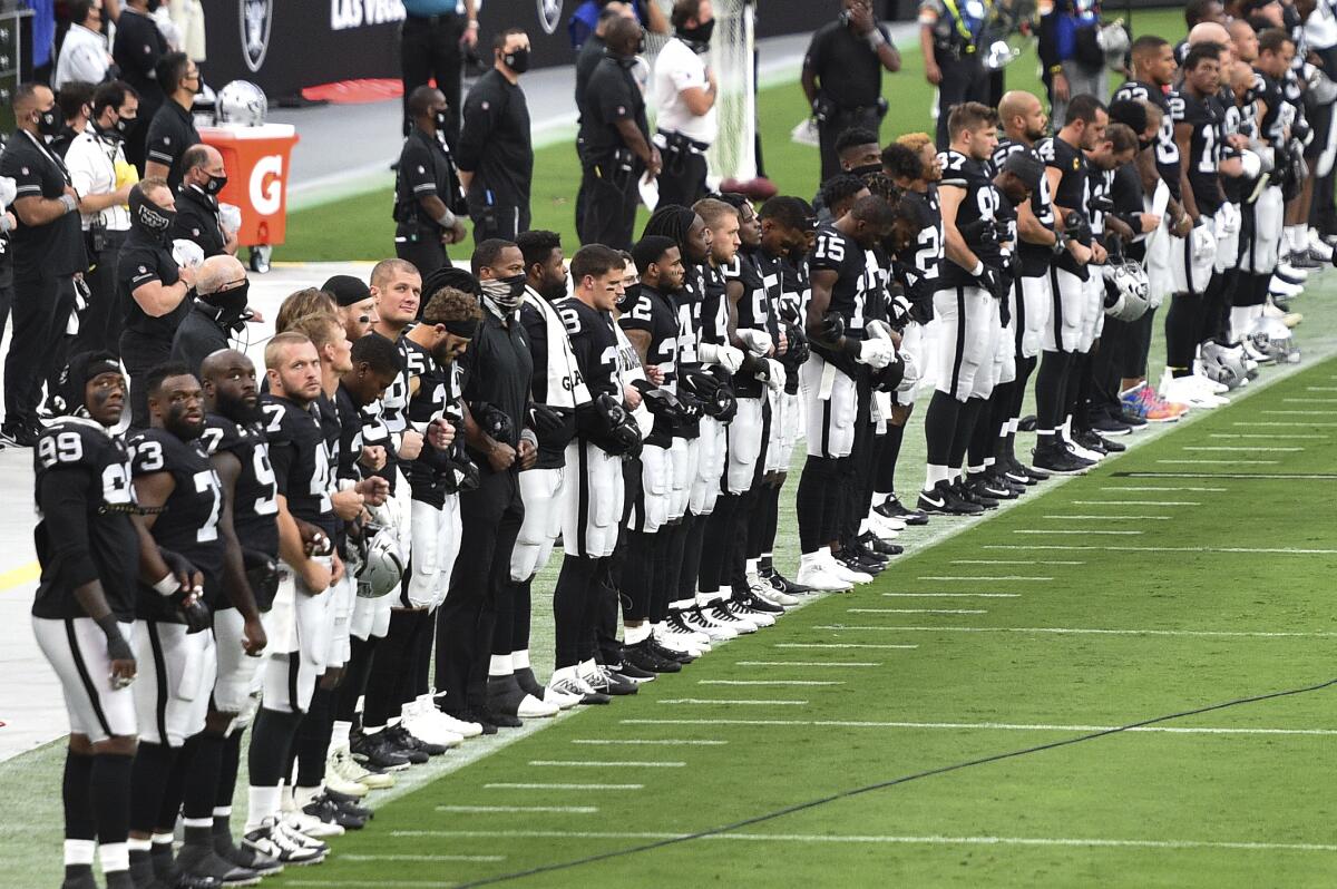 Jugadores de los Raiders de Las Vegas escuchan de pie el himno nacional 