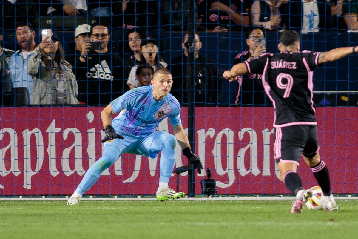 Galaxy goalkeeper John McCarthy crouches in front of the goal as Inter Miami CF player Luis Suárez approaches.
