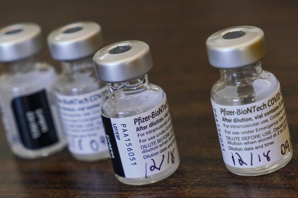 Viales de la vacuna Pfizer-BioNTech son colocados en una mesa mientras los enfermeros se preparan para vacunar
