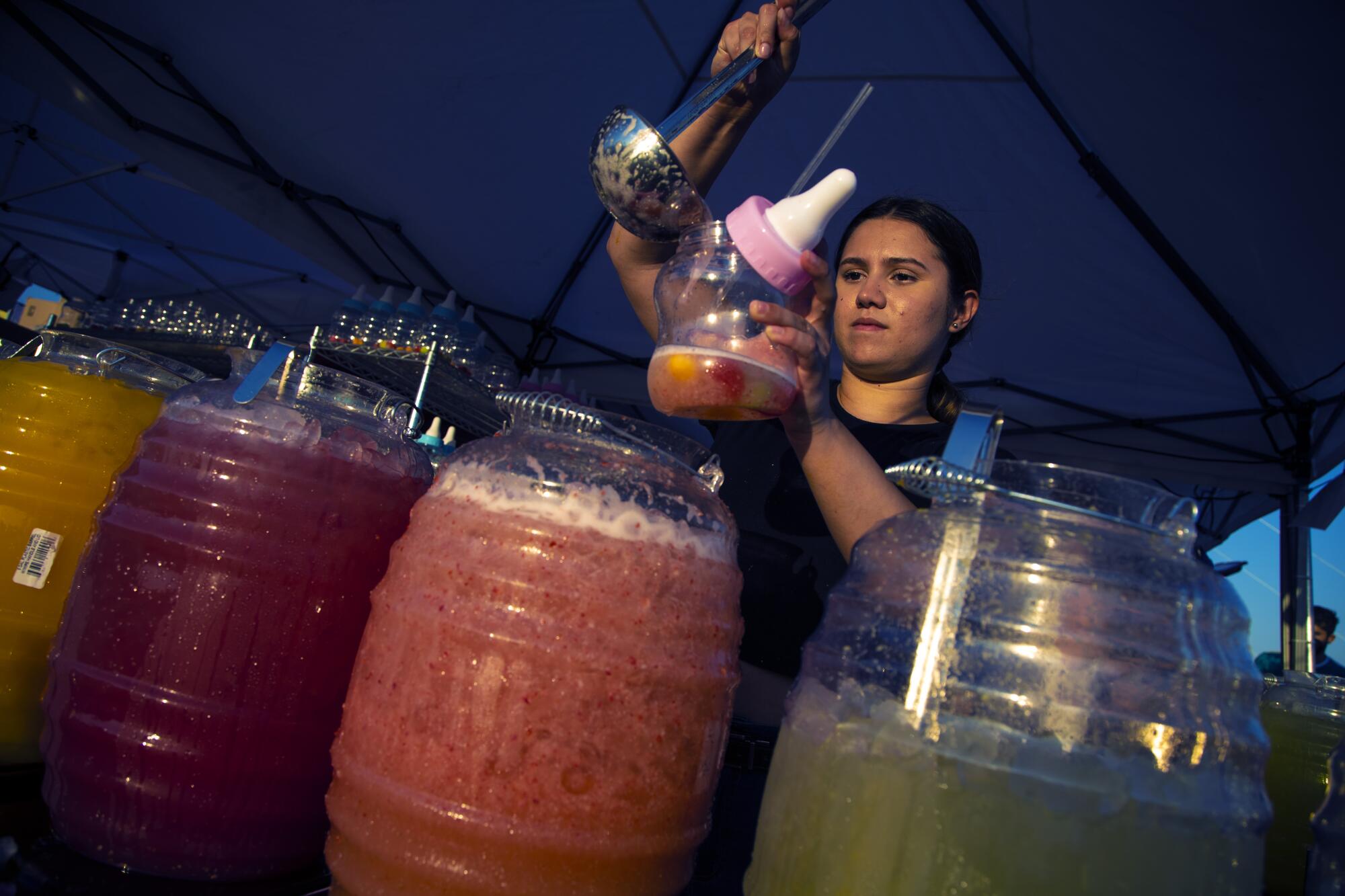 Gracie De Jesus fills large 'baby bottles' with aqua frescos at the 626 Night Market.