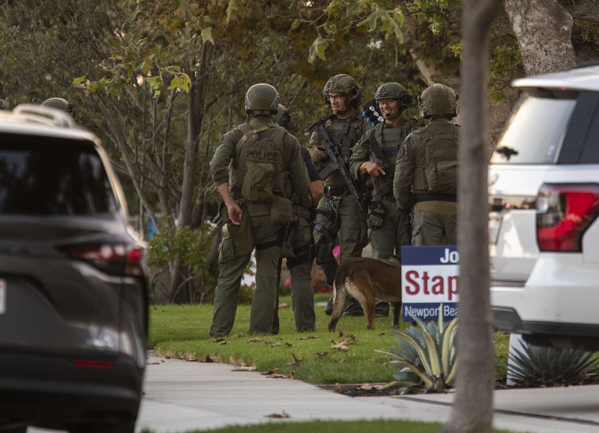 A SWAT team stages near a home where a person is barricaded after several carjackings in Newport Beach.