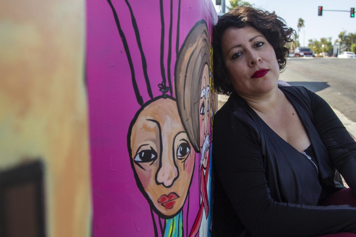 Yvette Roman poses next to her work of art she named "Titeres" outside Hilltop Liquor in San Diego, CA.