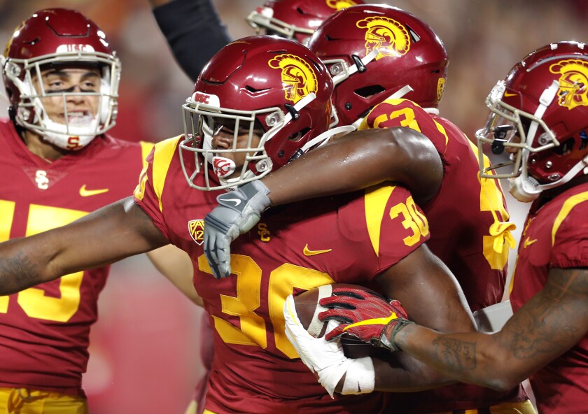 USC tailback Markese Stepp is swarmed by teammates after scoring a touchdown against Utah in the fourth quarter at the Coliseum on Friday.