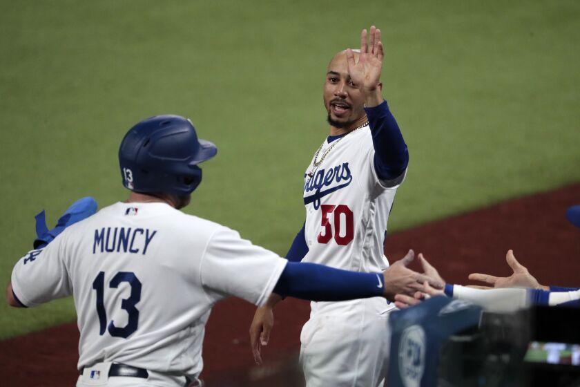 Arlington, Texas, Tuesday, October 6, 2020. Los Angeles Dodgers right fielder Mookie Betts (50) congratulates teammate Max Muncy during a sixth inning rally in game one of the NLDS at Globe Life Field. (Robert Gauthier/ Los Angeles Times)
