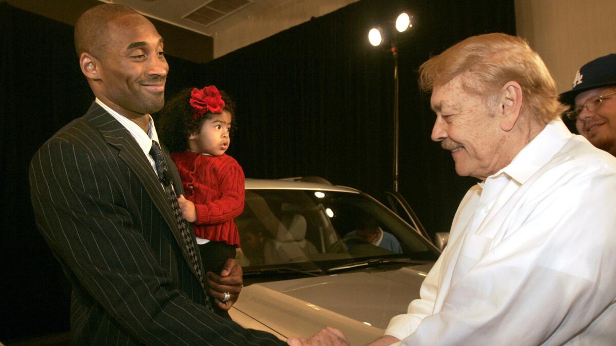 Kobe Bryant shakes hands with Jerry Buss while holding his daughter, Natalia.