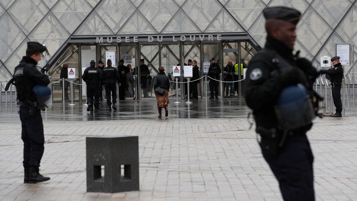 Armed police officers patrol in the courtyard of the Louvre Museum.