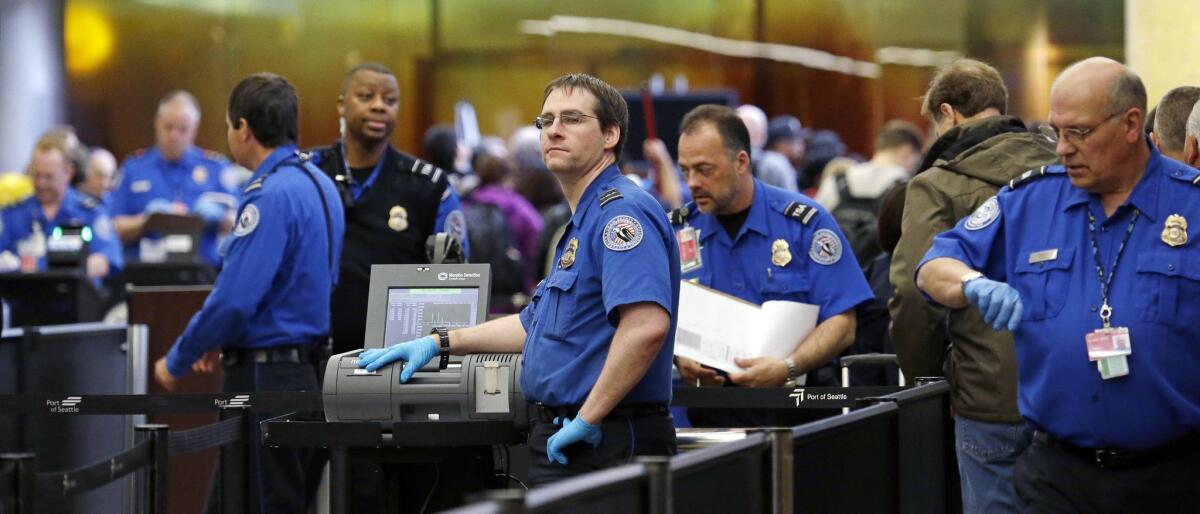 TSA agents work at a security checkpoint at Seattle-Tacoma International Airport in SeaTac, Wash.