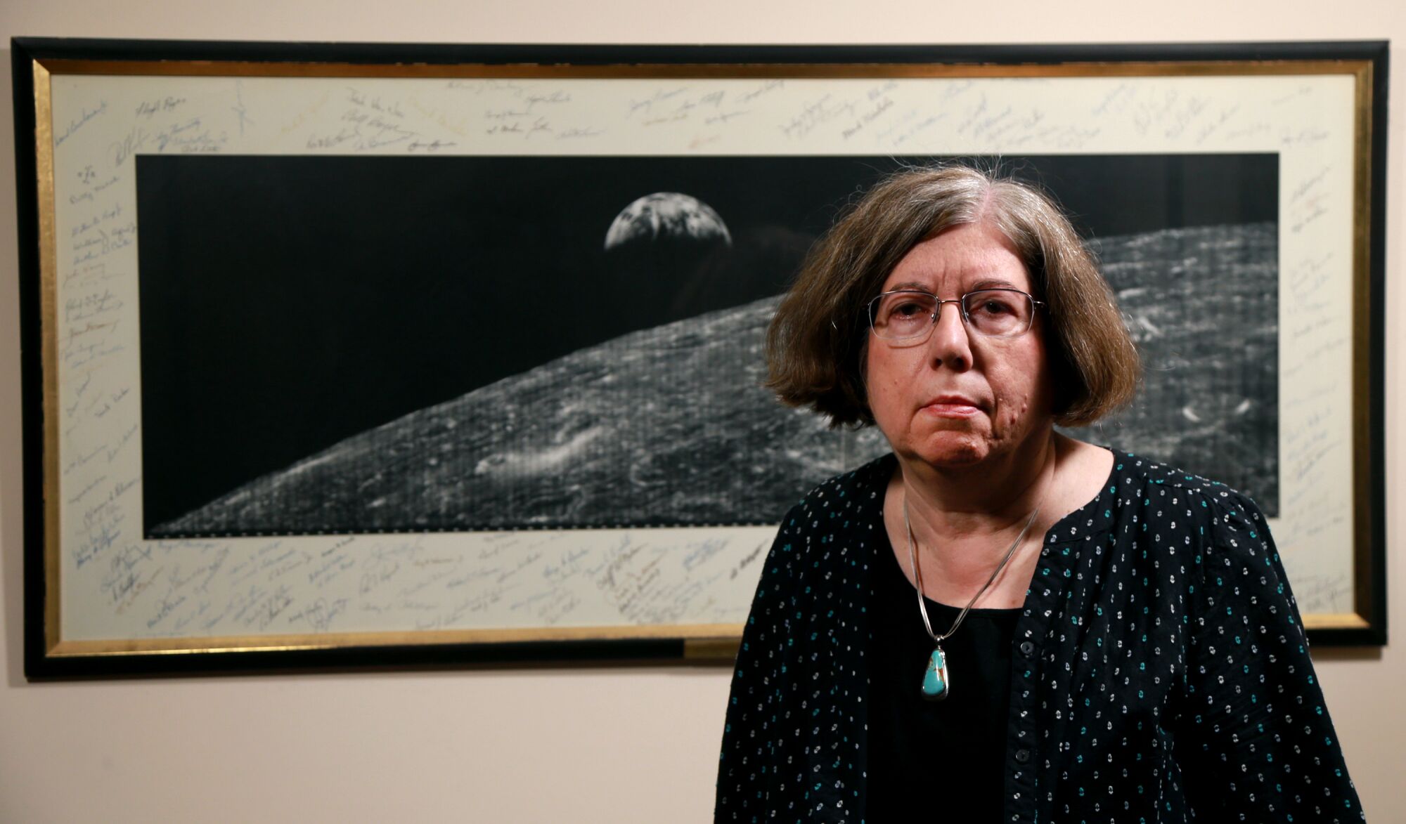 Judy Cook is the daughter of Abraham Silverstein, who was among a group of Jewish engineers who worked with former German rocket engineers under Adolf Hitler. Behind Cook is a photo of the Earth rising over the moon signed by fellow engineers.