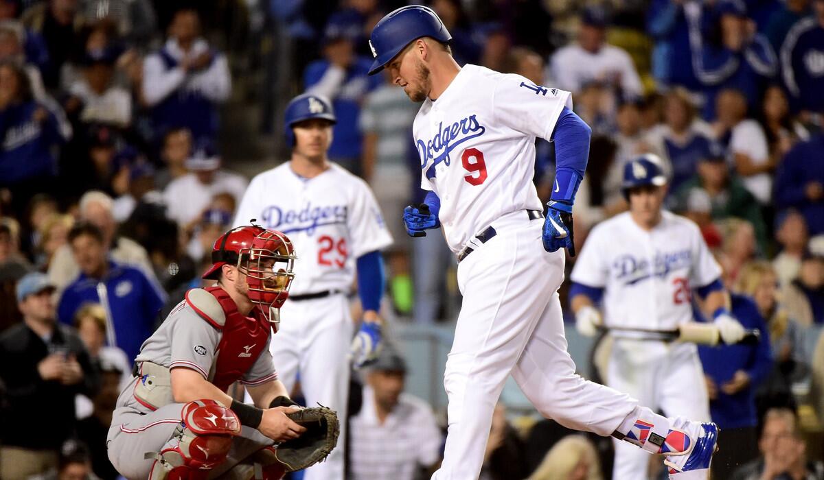 Dodgers catcher Yasmani Grandal scores a run in front of Cincinatti Reds catcher Tucker Barnhart from his solo homerun to take a 3-1 lead during the fifth inning at Dodger Stadium on Wednesday.