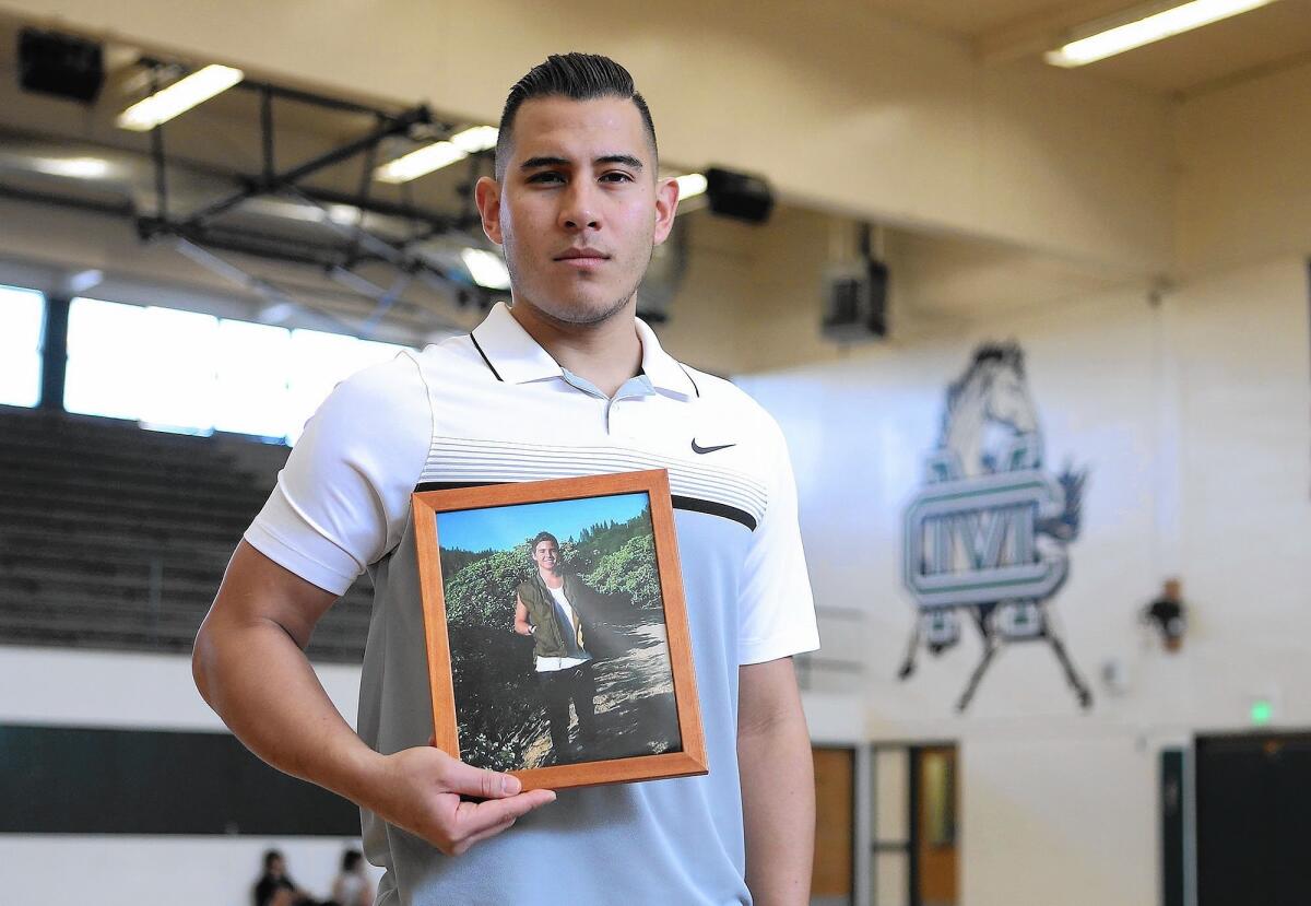 Mike Molina holds a picture of his friend Jeff Long who died of cancer in 2012. Molina, a Costa Mesa High alumnus and former boys' basketball coach, has started Coach Mike's Long Shot Challenge, a one-day boys' basketball showcase to raise money for pediatric cancer. Molina also recently battled cancer himself.