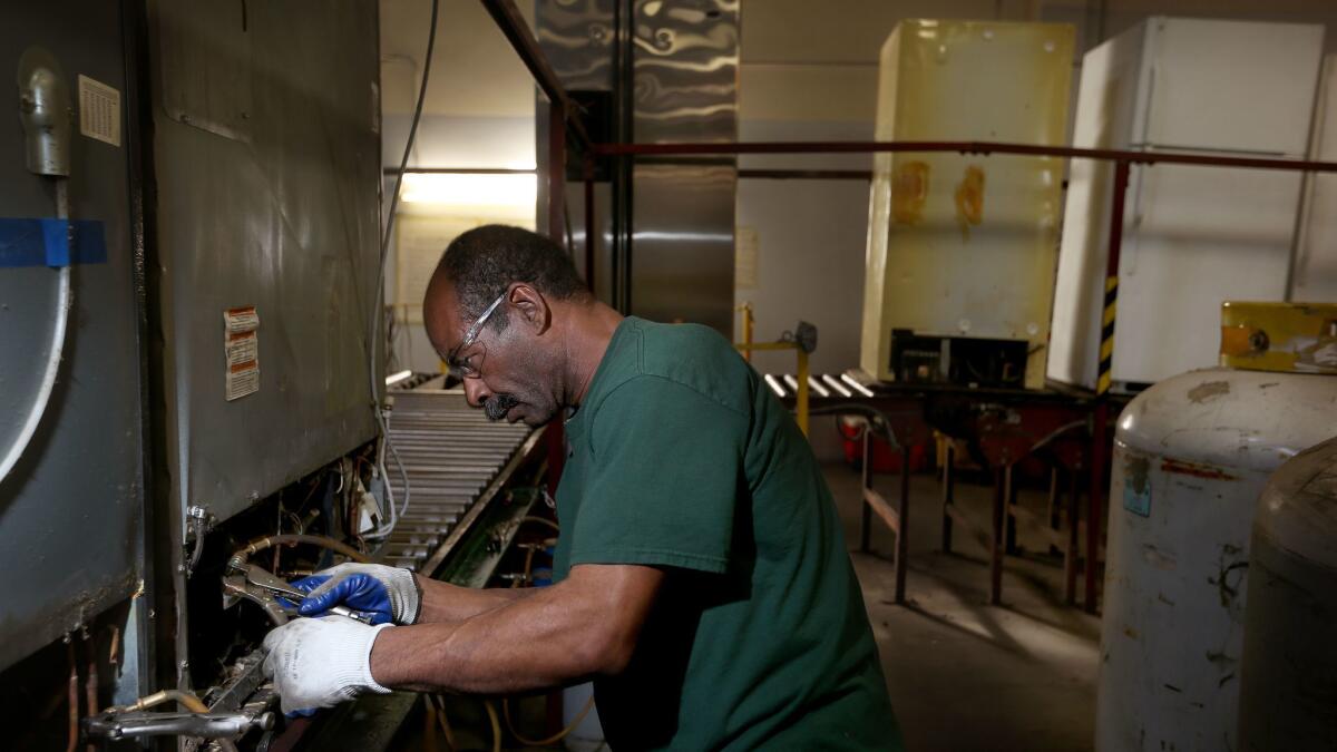 Delbert Hart, 54, works to remove coolants from refrigerators at a Compton facility as part of California's cap-and-trade program.