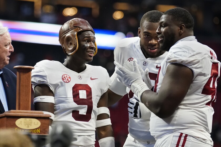 Alabama quarterback Bryce Young (9) wears the leather helmet from the "Old Leather Helmet Trophy" as he, Evan Neal (73) and Phidarian Mathis (48) celebrate their win over Miami in the Chick-fil-A Kickoff NCAA college football game Saturday, Sept. 4, 2021, in Atlanta. (AP Photo/John Bazemore)