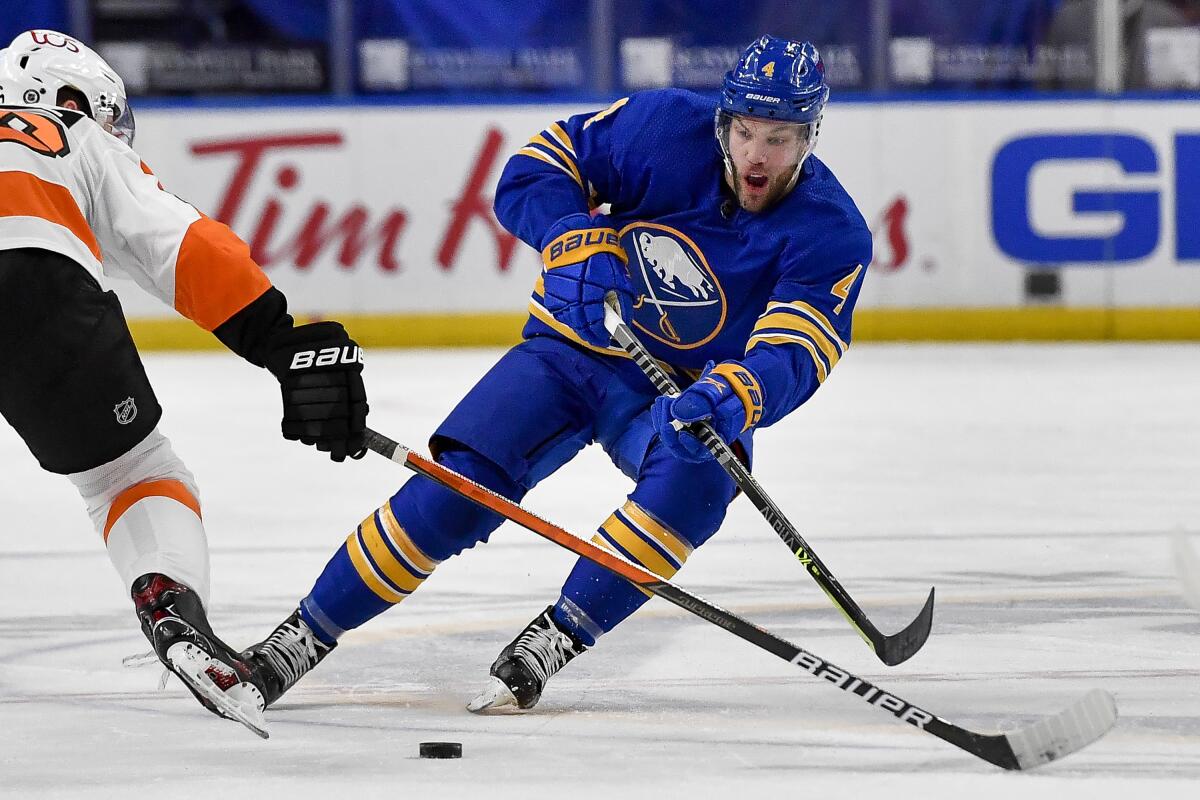 Buffalo Sabres left wing Taylor Hall passes the puck while pressured by Philadelphia Flyers center Joel Farabee.